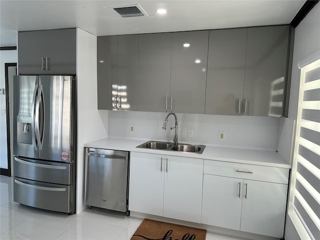 kitchen with gray cabinetry, sink, light tile patterned flooring, and appliances with stainless steel finishes