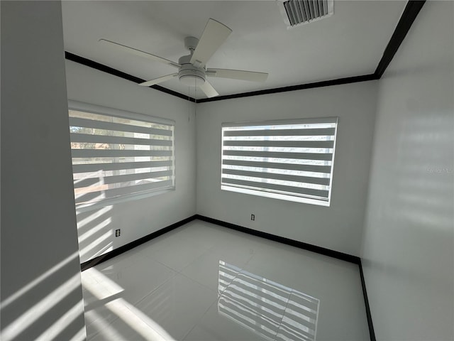 spare room with ceiling fan, ornamental molding, and light tile patterned floors