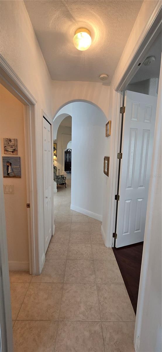 hallway featuring a textured ceiling and light tile patterned floors