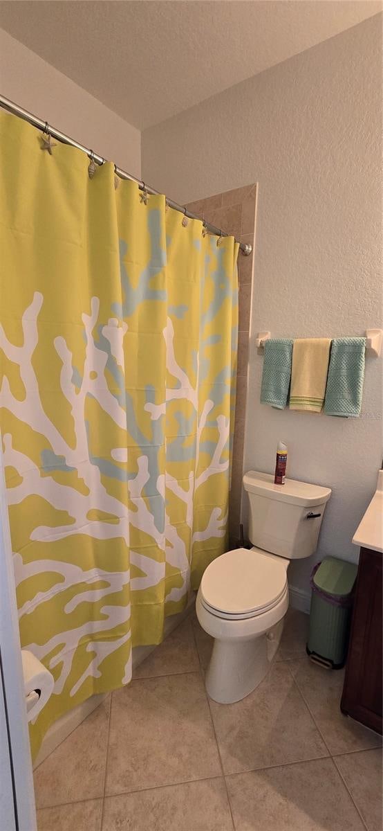 bathroom featuring vanity, toilet, walk in shower, and tile patterned flooring