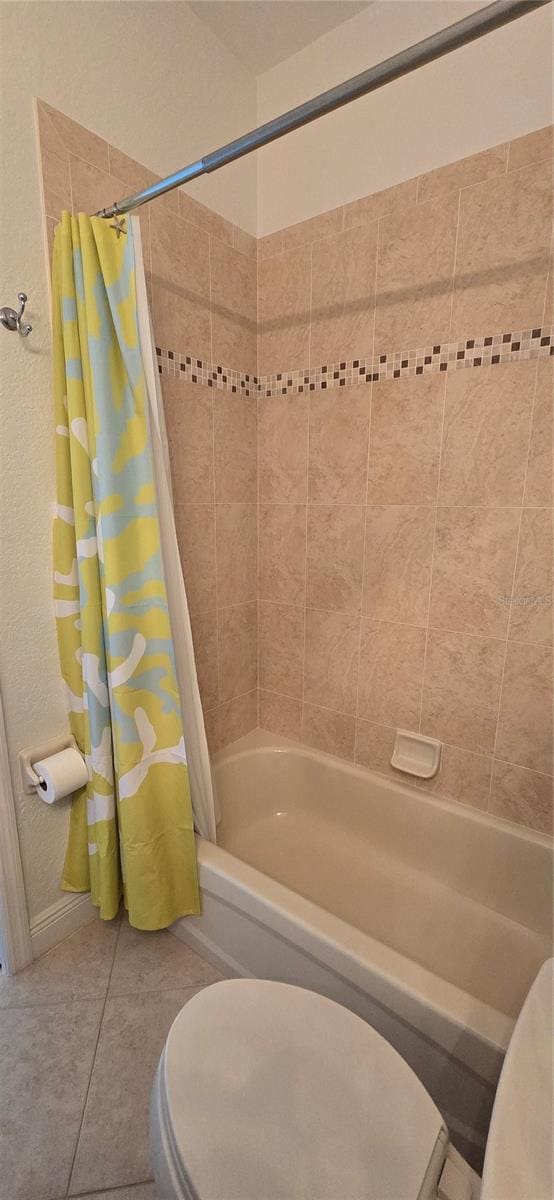 bathroom featuring toilet, shower / bathtub combination with curtain, and tile patterned floors