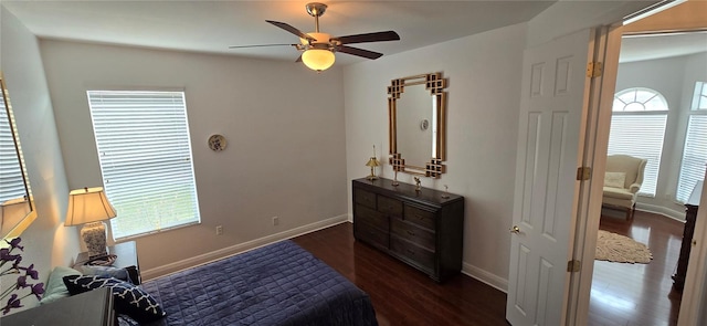 bedroom featuring ceiling fan, multiple windows, and dark hardwood / wood-style floors