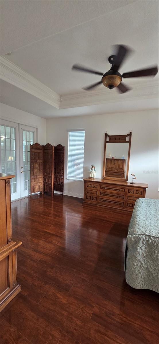 bedroom featuring ceiling fan, a tray ceiling, dark wood-type flooring, crown molding, and french doors