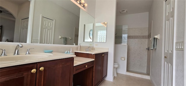 bathroom with vanity, toilet, tile patterned floors, and a tile shower