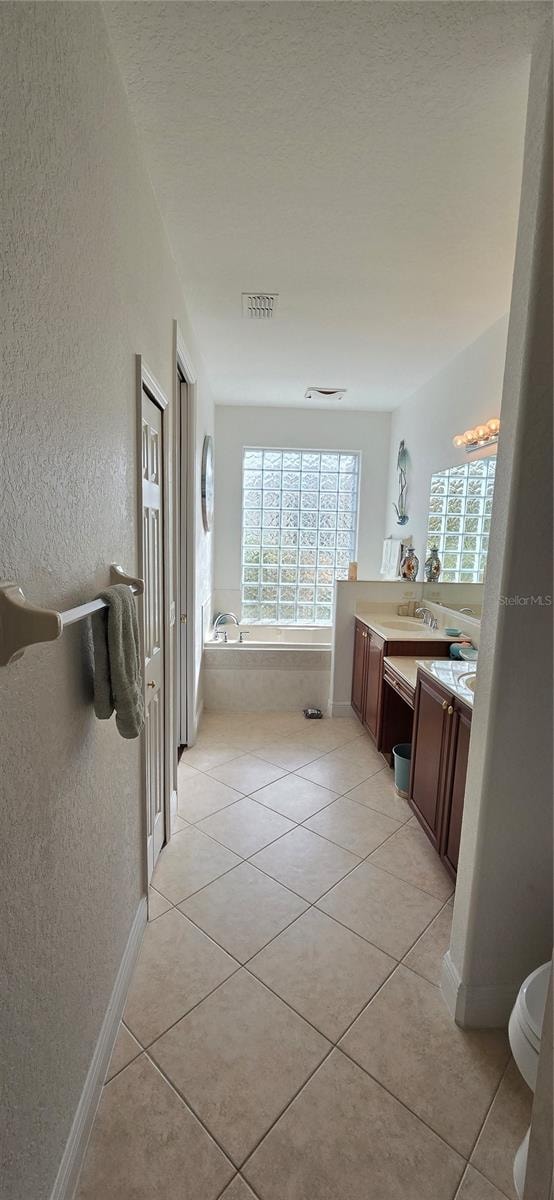 bathroom with vanity, a tub, toilet, and tile patterned floors