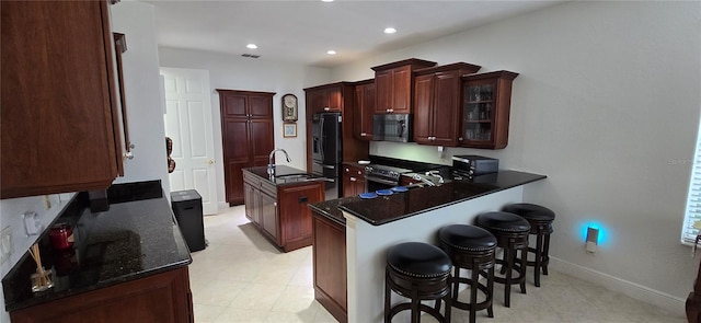 kitchen with appliances with stainless steel finishes, sink, a kitchen bar, kitchen peninsula, and a center island with sink