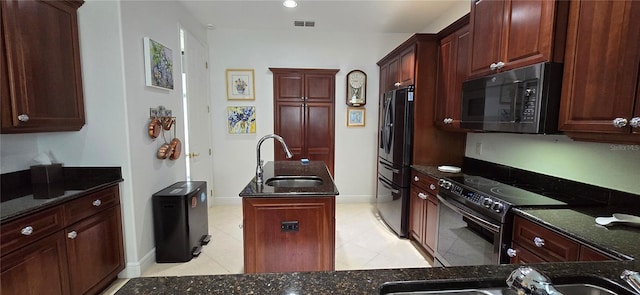 kitchen with a kitchen island, stainless steel appliances, dark stone countertops, sink, and light tile patterned flooring