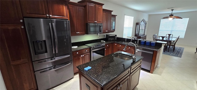 kitchen featuring a kitchen island, kitchen peninsula, stainless steel appliances, dark stone countertops, and sink