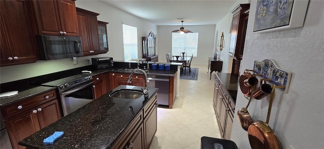 kitchen featuring appliances with stainless steel finishes, dark stone countertops, decorative light fixtures, and sink