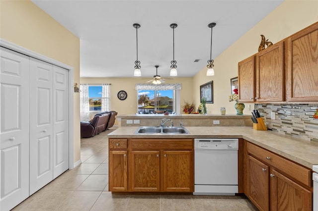 kitchen with white dishwasher, sink, kitchen peninsula, and hanging light fixtures