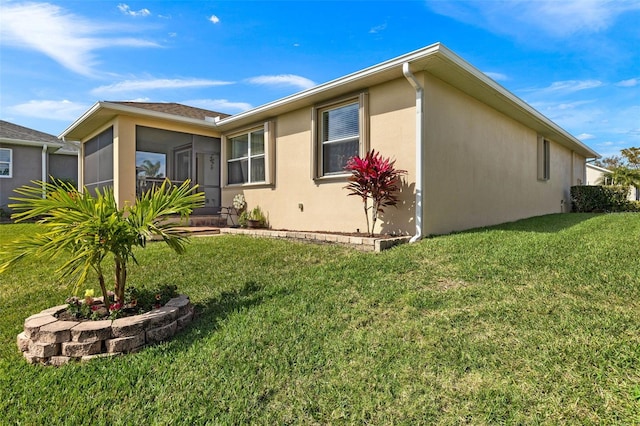 rear view of property with a lawn and a sunroom