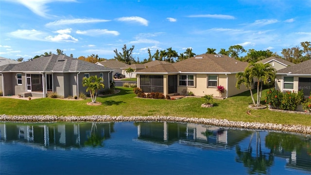 rear view of property with a water view, a sunroom, and a lawn