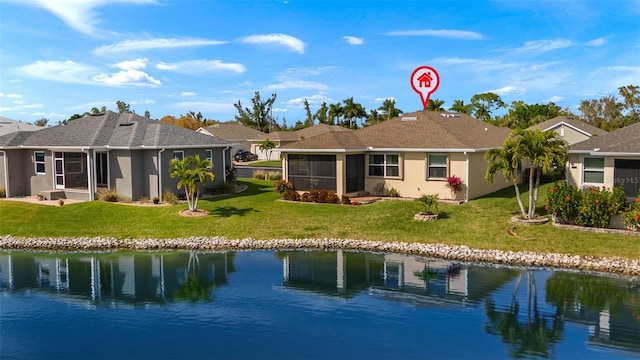 back of property featuring a yard, a water view, and a sunroom