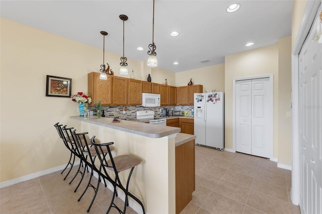 kitchen with a breakfast bar area, tasteful backsplash, hanging light fixtures, kitchen peninsula, and white appliances