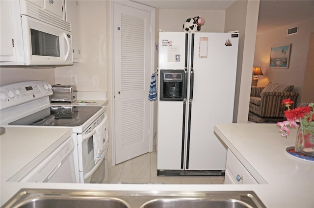 kitchen with white appliances, light tile patterned floors, and white cabinets