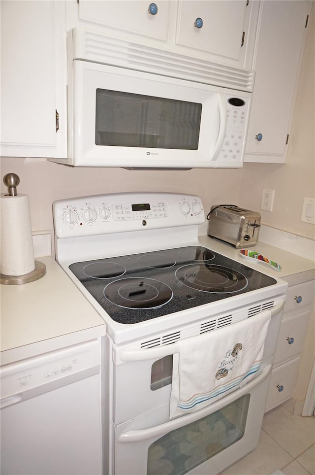 kitchen with white appliances, white cabinetry, and light tile patterned floors