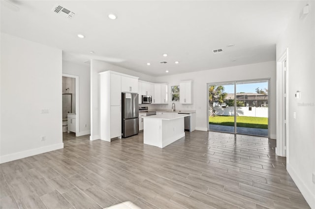 kitchen featuring appliances with stainless steel finishes, sink, a center island, light hardwood / wood-style floors, and white cabinets