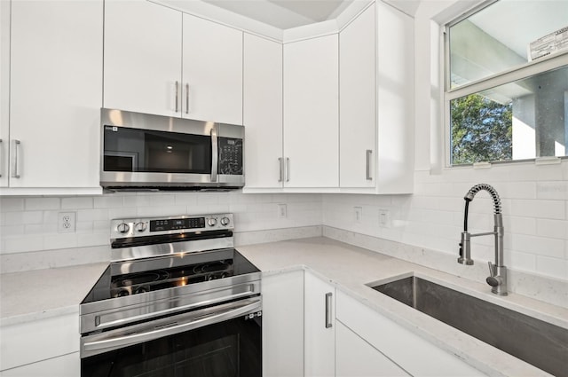 kitchen featuring appliances with stainless steel finishes, white cabinetry, sink, and backsplash