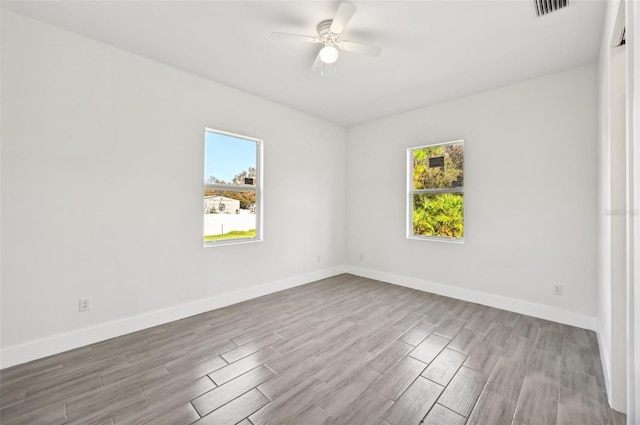 empty room with ceiling fan, hardwood / wood-style flooring, and plenty of natural light