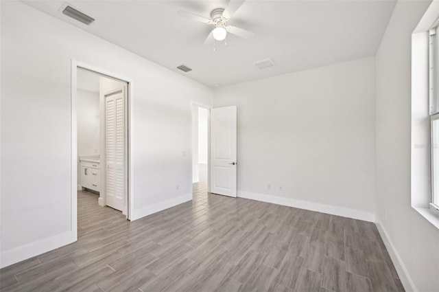 unfurnished bedroom with ensuite bath, a closet, light hardwood / wood-style floors, and ceiling fan