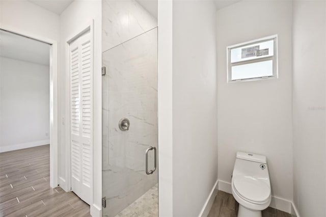 bathroom featuring toilet, a shower with shower door, and hardwood / wood-style floors