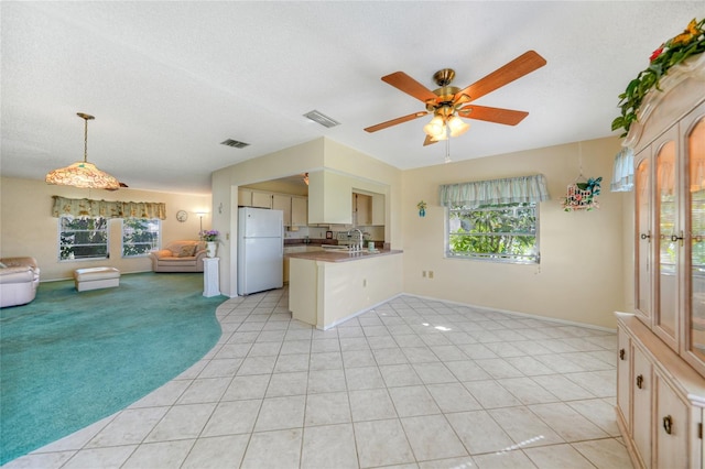 kitchen featuring sink, kitchen peninsula, ceiling fan, white fridge, and light tile patterned floors