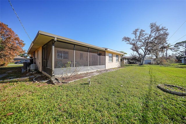 rear view of property with a lawn and a sunroom