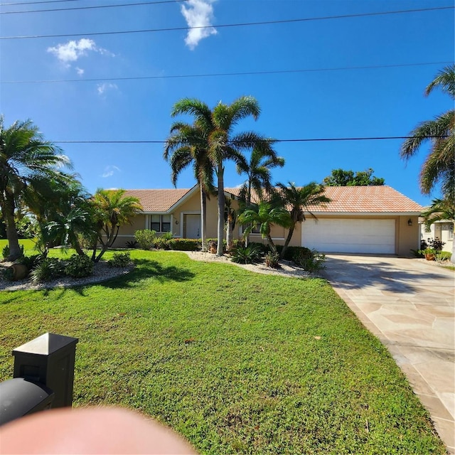 ranch-style home featuring a tiled roof, a front yard, stucco siding, driveway, and an attached garage