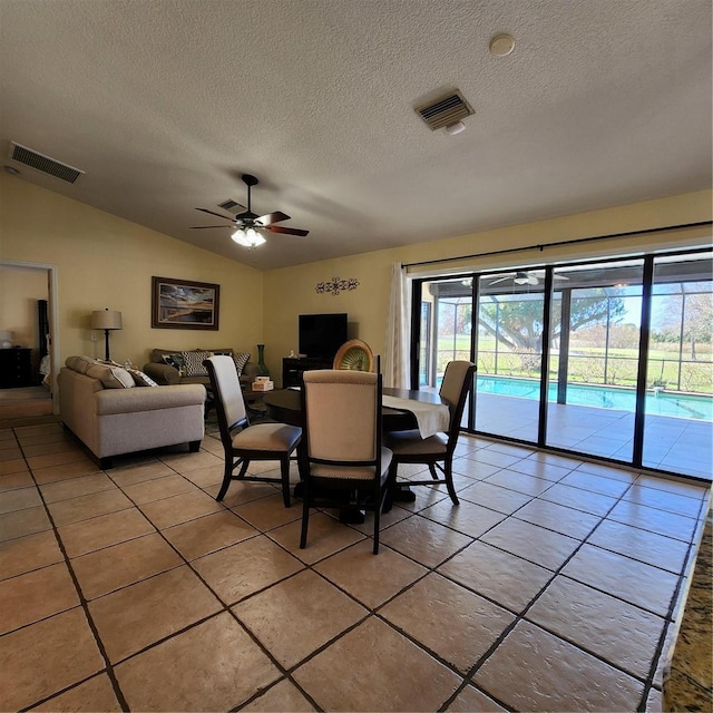 dining room featuring lofted ceiling, light tile patterned flooring, a textured ceiling, and ceiling fan