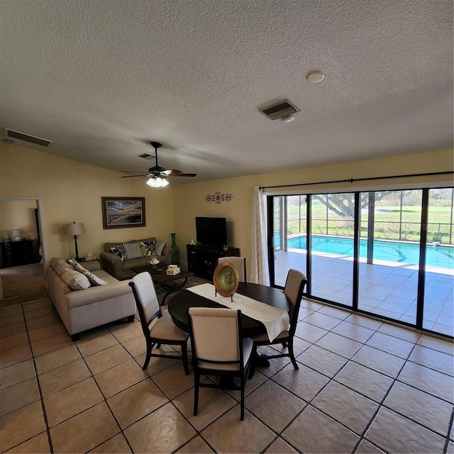 dining space with a textured ceiling, light tile patterned floors, and ceiling fan