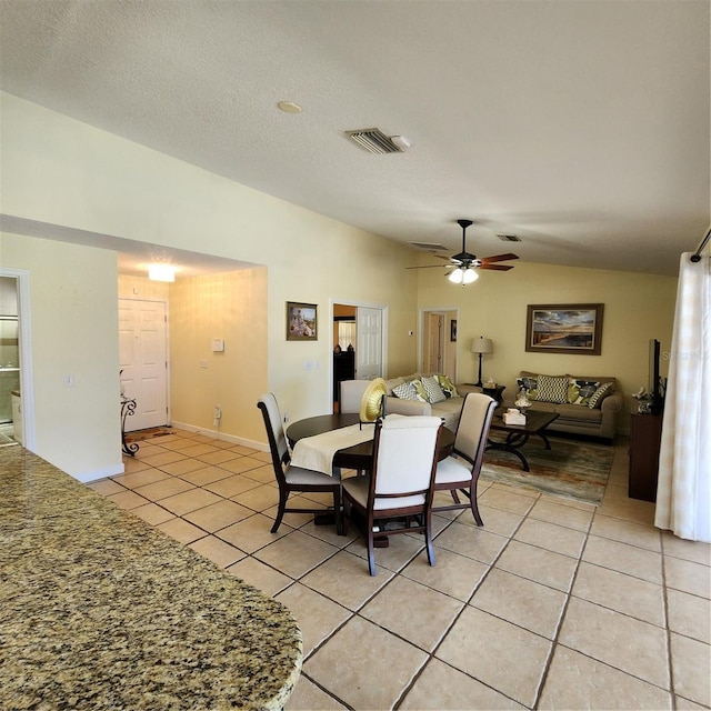 dining room with a textured ceiling, ceiling fan, light tile patterned flooring, and vaulted ceiling