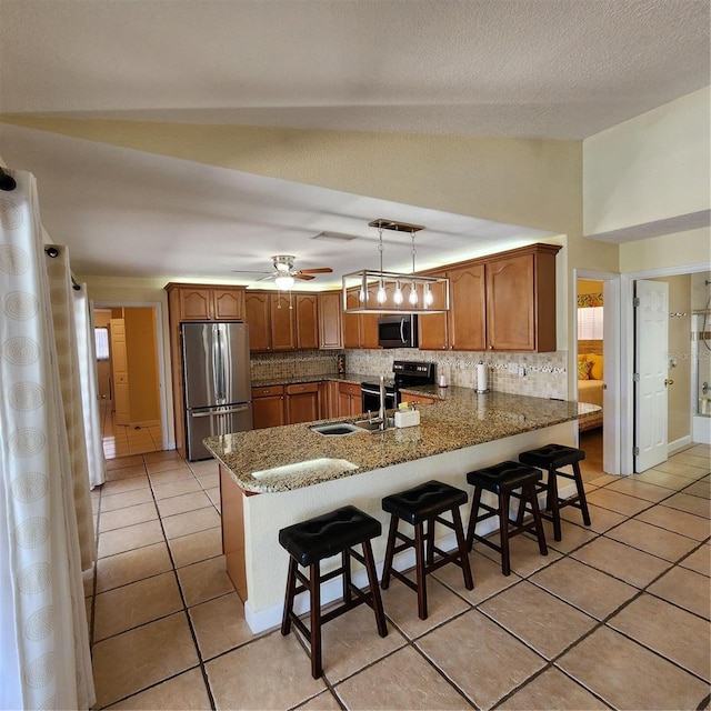 kitchen with a kitchen breakfast bar, tasteful backsplash, stainless steel appliances, and hanging light fixtures