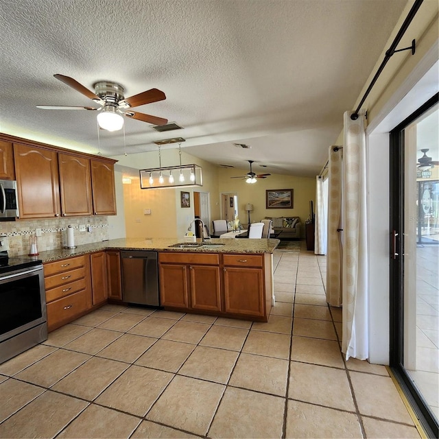 kitchen featuring kitchen peninsula, stainless steel appliances, sink, decorative light fixtures, and tasteful backsplash