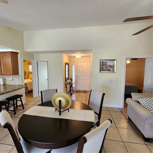 dining area featuring a textured ceiling, ceiling fan, and light tile patterned floors