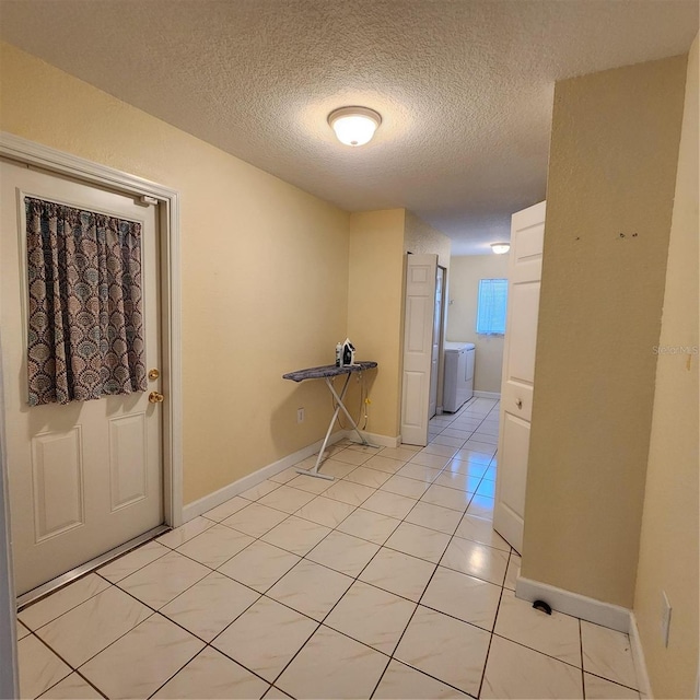 hall with a textured ceiling, light tile patterned floors, and separate washer and dryer