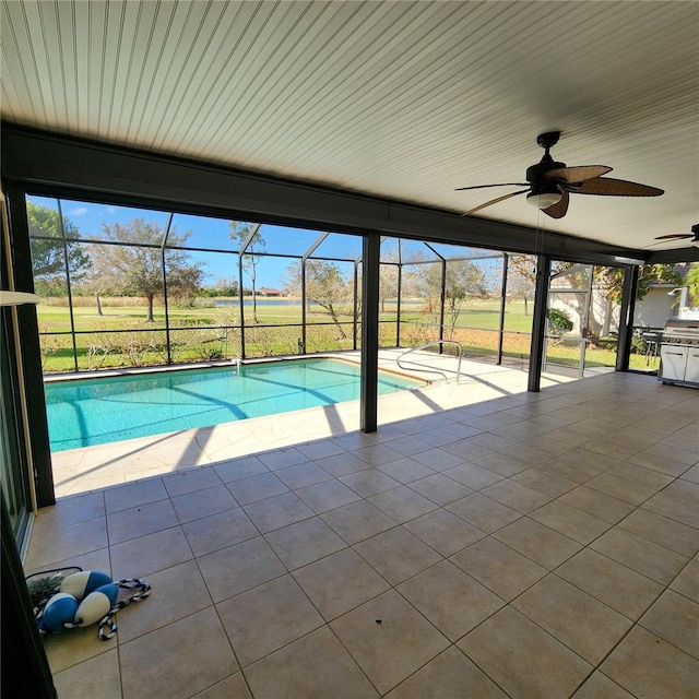 view of pool featuring a patio area, glass enclosure, and ceiling fan