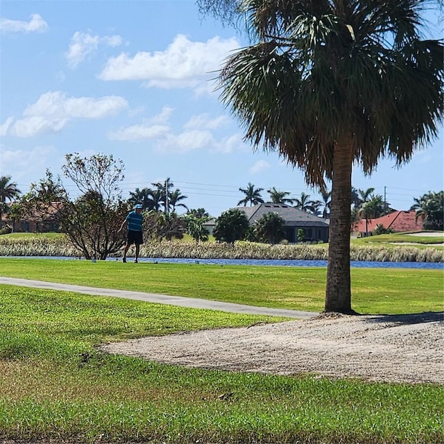 view of home's community with a water view and a lawn