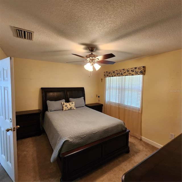 carpeted bedroom featuring ceiling fan and a textured ceiling