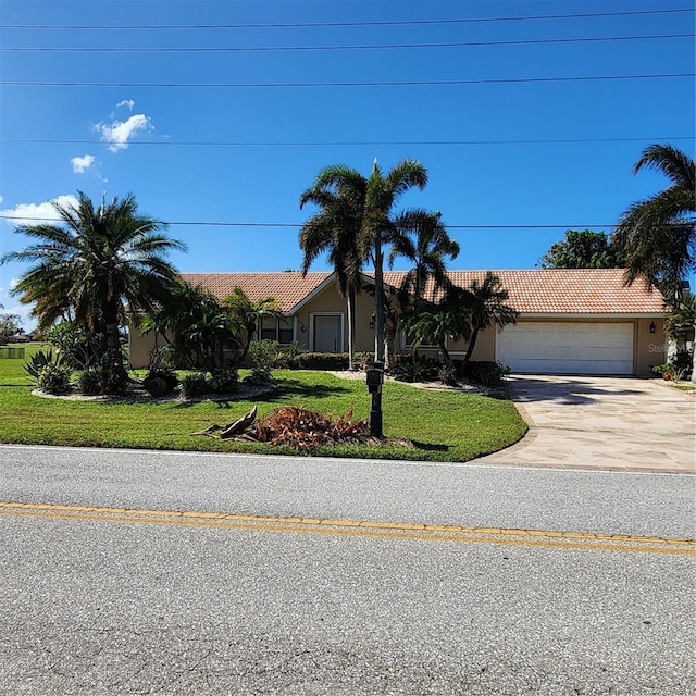 view of front of property featuring stucco siding, a front lawn, driveway, a tile roof, and a garage