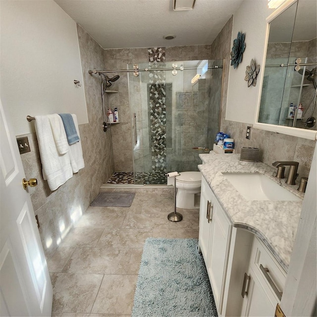 full bath featuring vanity, a shower stall, toilet, and tile walls