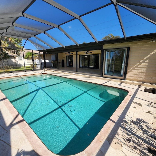 outdoor pool featuring glass enclosure, a patio, and ceiling fan