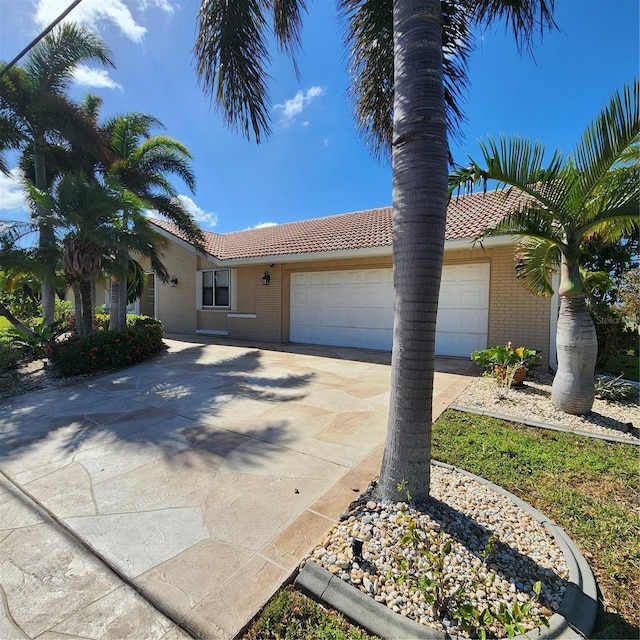 view of front of home with brick siding, a tiled roof, concrete driveway, and a garage