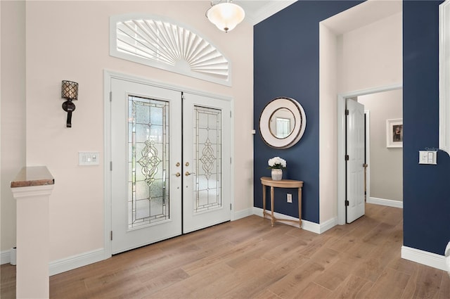 entryway with ornamental molding, light hardwood / wood-style flooring, and french doors