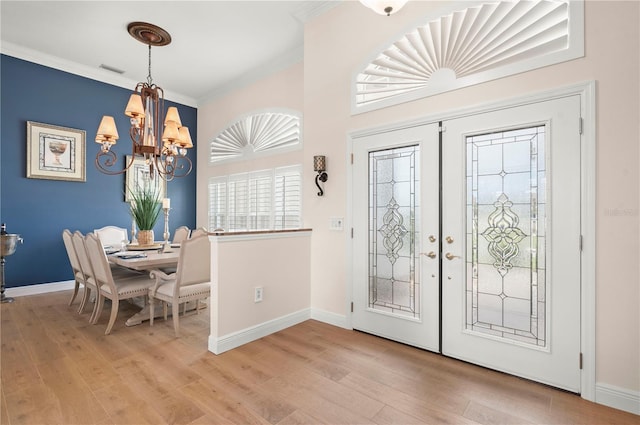 foyer with a chandelier, crown molding, french doors, and light wood-type flooring