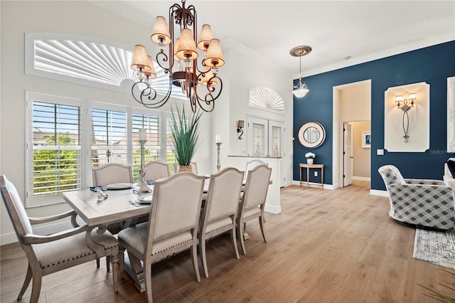 dining area with light hardwood / wood-style flooring, crown molding, and a chandelier