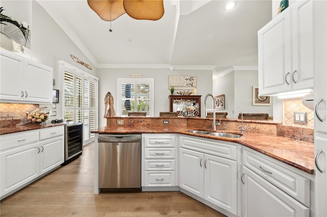 kitchen with beverage cooler, white cabinets, dishwasher, sink, and kitchen peninsula