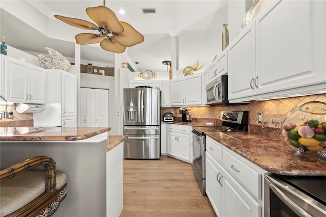 kitchen featuring ceiling fan, dark stone countertops, light hardwood / wood-style flooring, appliances with stainless steel finishes, and white cabinets