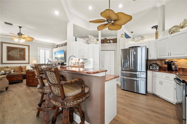 kitchen with white cabinets, backsplash, appliances with stainless steel finishes, and a breakfast bar area