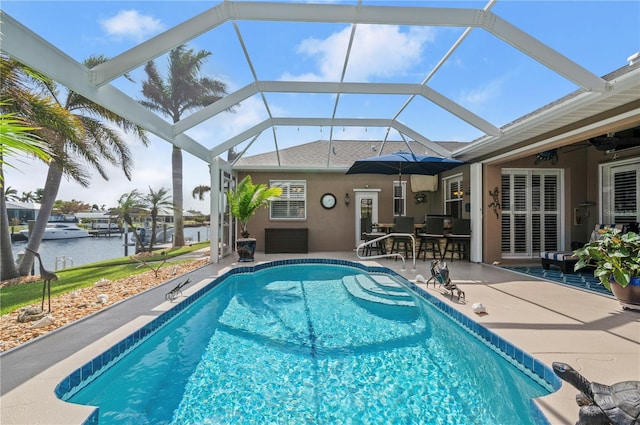 view of pool with a lanai, ceiling fan, a patio area, and a water view