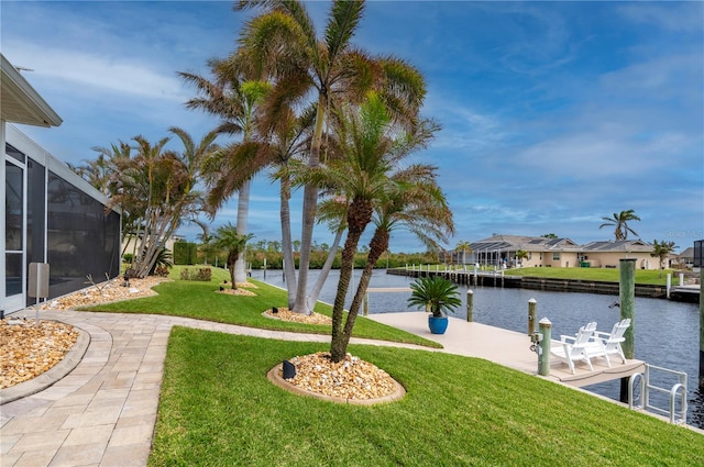 view of yard with glass enclosure, a water view, and a dock